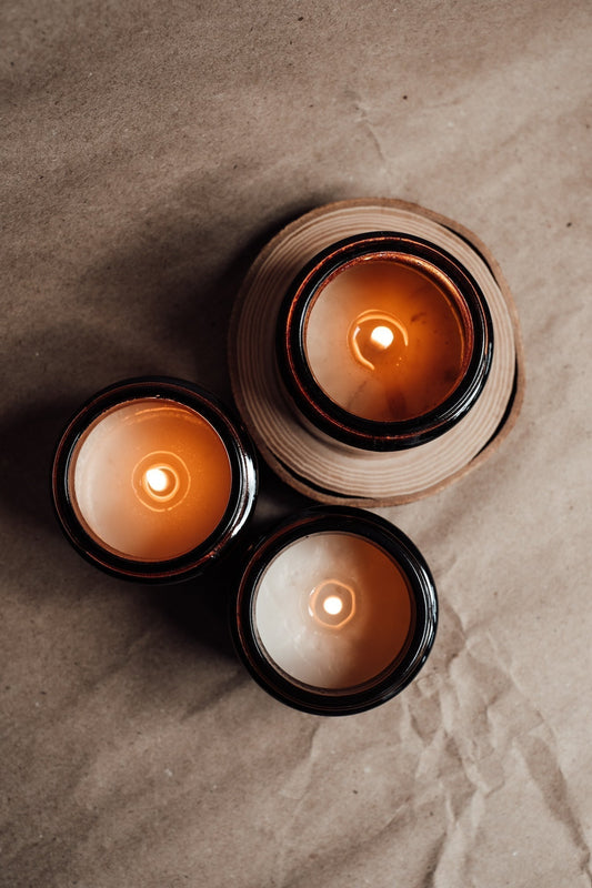 Minimalist nontoxic candle lit on a bedside table, surrounded by soft blankets and a book—creating a peaceful, calming atmosphere for anxiety relief.